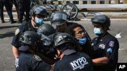FILE - A Black Lives Matter protester is apprehended by NYPD officers on Brooklyn Bridge in New York, July 15, 2020.