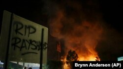 "RIP Rayshard" terlihat pada sebuah papan ketika api menelan restoran Wendy selama protes Sabtu, 13 Juni 2020, di Atlanta. (Foto: AP/Brynn Anderson)