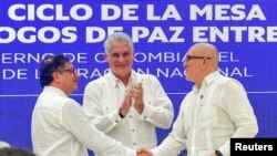 El presidente de Colombia, Gustavo Petro (izquierda), y el comandante del ELN, Antonio García, se dan la mano mientras el presidente de Cuba, Miguel Díaz-Canel, aplaude, durante el anuncio del alto el fuego, en La Habana, Cuba. Presidencia de Colombia/vía REUTERS 