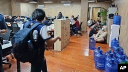 Dalam foto selebaran yang disediakan oleh Polisi Nasional Filipina, tampak seorang polisi berjalan di dalam salah satu kantor kejahatan siber yang mereka razia di kota Las Pinas, Filipina hari Selasa 27 Juni 2023.