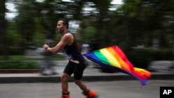 Un hombre de la comunidad LGBT pasa patinando con una BANDERA de arcoíris para celebrar la diversidad sexual, en Ciudad de México, el 26 de junio de 2021.