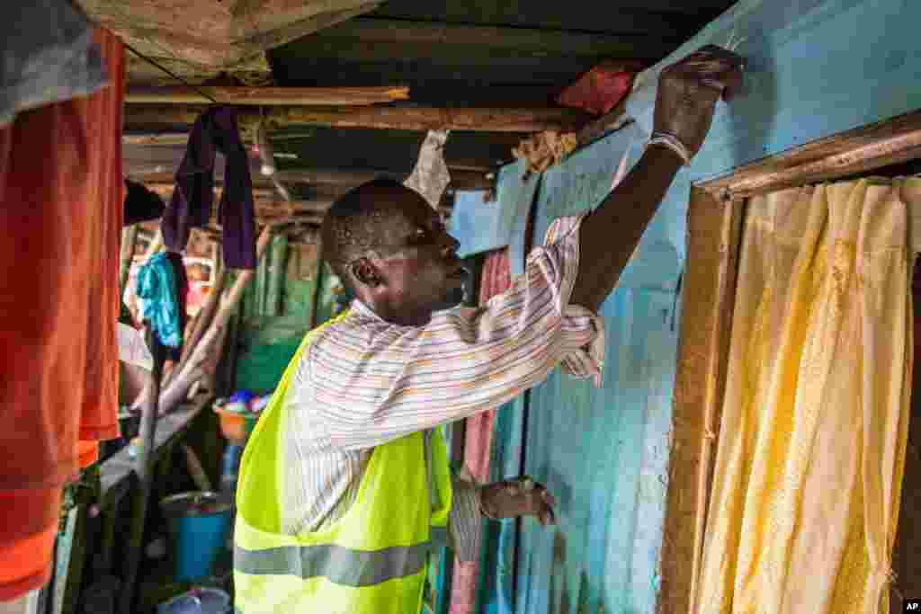 Seorang relawan medis menandai sebuah rumah dengan coretan kapur, sebagai tanda bahwa rumah tersebut telah dikunjungi petugas yang mendistribusikan sabun dan informasi tentang virus Ebola di Freetown, Sierra Leone (20/9).