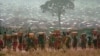 FILE - Refugees who fled the genocide in Rwanda carry water containers back to their huts at a refugee camp in Tanzania on May 17, 1994. French President Emmanuel Macron reportedly will say on April 7, 2024, that the genocide could have been stopped by France and its allies.