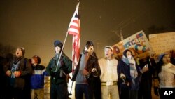 Pengunjuk rasa berdiri di depan kantor polisi Ferguson (26/11/ 2014) mengecam pengadilan yang tidak mendakwa polisi kulit putih yang menembak mati remaja kulit hitam yang tak bersenjata di Ferguson, Missouri.