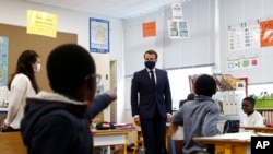 French President Emmanuel Macron speaks with schoolchildren during a class at the Pierre Ronsard elementary school, May 5 2020, outside Paris. Starting from May 11 schools will start gradually reopening.