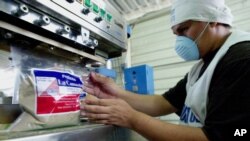 Roberto Evora, un empleado de "La Canasta", fabricantes de especias secas y bebidas en polvo, sella una bolsa de un producto que se exportará al mercado estadounidense en Santa Tecla, El Salvador, el jueves 5 de mayo de 2005. 