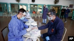 Un trabajador sanitario le hace una prueba de COVID-19 el pasado 13 de octubre a un maestro en la escuela Hipólito Yrigoyen en Buenos Aires, donde se han empezado a relajar las restricciones.