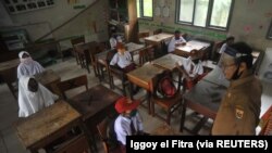 Siswa dan guru memakai masker pelindung setelah pemerintah Indonesia membuka kembali sekolah dengan menerapkan proses pembelajaran tatap muka di tengah wabah Covid-19 di Pariaman, Provinsi Sumatera Barat, 13 Juli 2020. (Foto: Antar /Iggoy el Fitra/via Reu