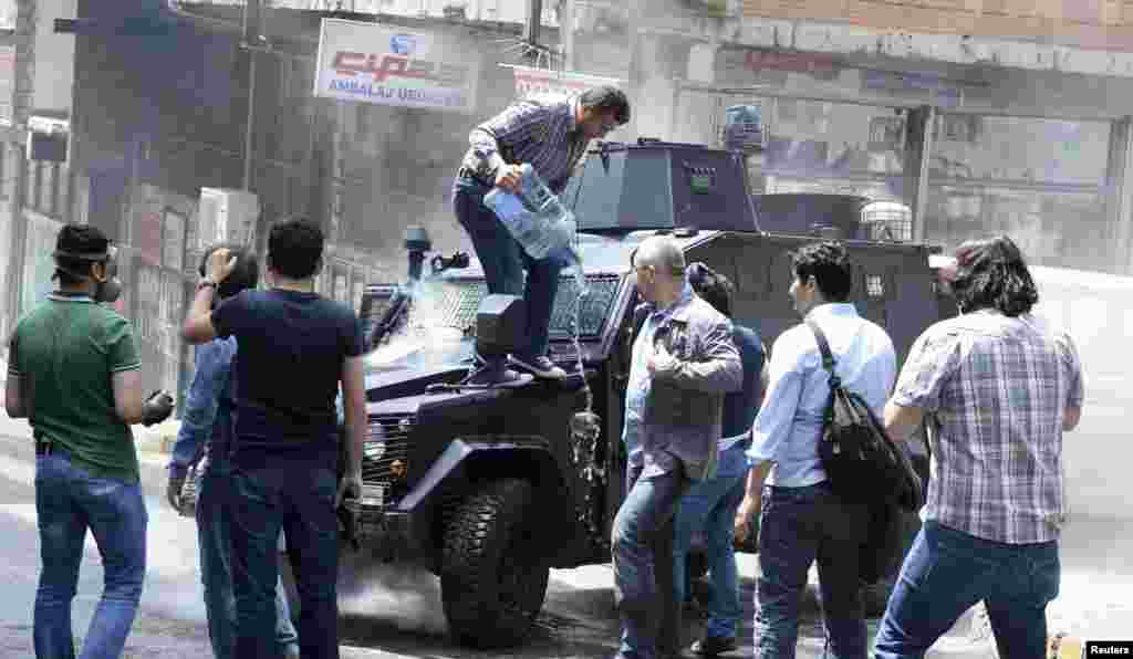 Okmeydanı'nda yanan polis aracına insanlar su döküyor