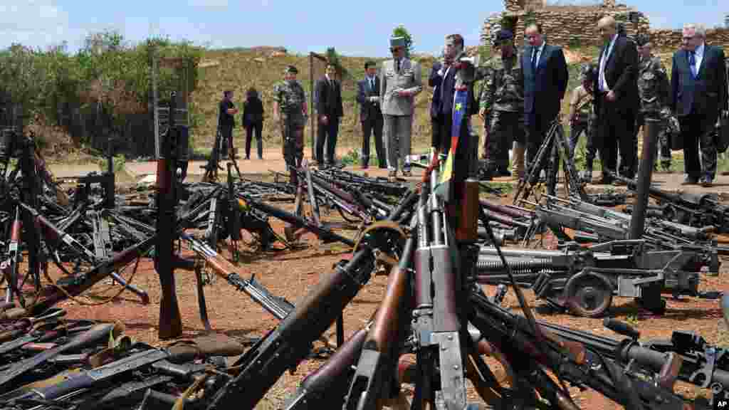 Le président français François Hollande, troisième à droite, et son ministre de la Défense Jean-Yves Le Drian, deuxième à droite, passent en revue des armes confisquées aux ex-rebelles Séléka et les milices anti-alaka par les militaires français de l'opération Sangaris, dans une base militaire française à Bangui, en République centrafricaine, l28 février 2014. (AP photo / Sia Kambou, Pool)