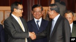 Cambodian Prime Minister Hun Sen, second from right, shakes hands with the main opposition party leader Sam Rainsy, left, of Cambodia National Rescue Party, as Deputy Prime Minister Sar Kheng, second from left, looks on after a meeting in Senate headquarters, Phnom Penh, Cambodia, July 22, 2017)