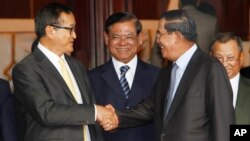 Cambodian Prime Minister Hun Sen, left, shakes hands with opposition party leader Sam Rainsy, right, after a meeting, as Sar Kheng, center, deputy prime minister, looks on at the National Assembly in Phnom Penh, Cambodia, Monday, Sept. 16, 2013.