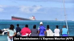 Des spectateurs regardent le vraquier Wakashio qui s'est échoué et dont le pétrole fuit près du parc marin de Blue Bay, dans le sud-est de l'île Maurice, le 6 août 2020. (Photo by Dev Ramkhelawon / L'Express Maurice / AFP)