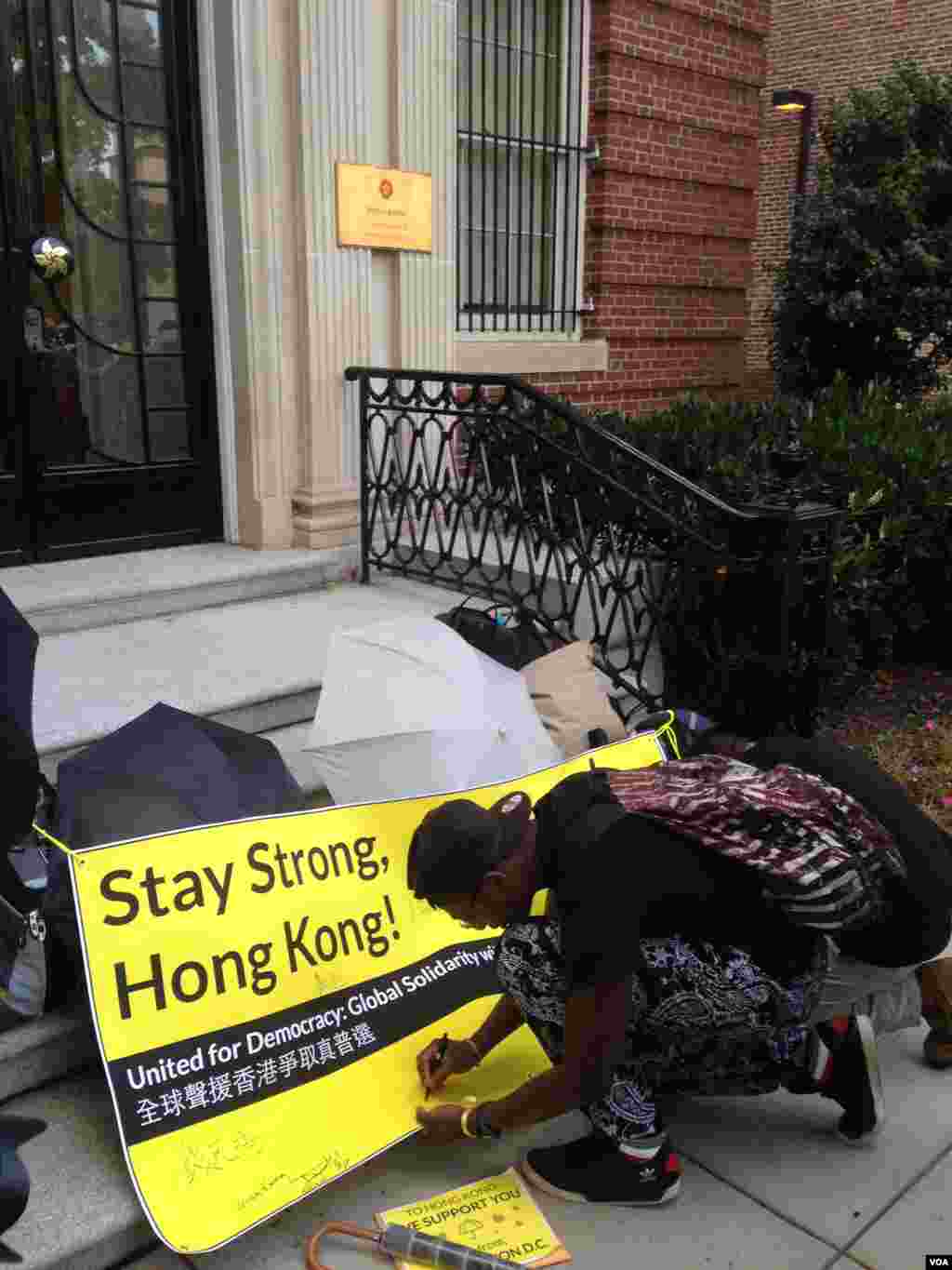 Supporters of Hong Kong’s pro-democracy movement sign a banner outside the Hong Kong Economic & Trade Office in Washington, Oct. 1, 2014. (Michael Lipin/VOA)