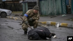 Ukrajinski vojnik proverava da na telu civila u Buči nema eksploziva (Foto: AP/Vadim Ghirda) 