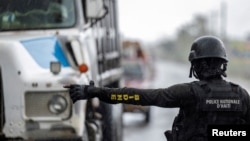 ARCHIVO - Un oficial de la Policía Nacional de Haití detiene a un camión en un control de seguridad en Limonade, Haití, el 27 de abril de 2024.