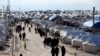 FILE - Women walk through al-Hol displacement camp in Hasaka governorate, Syria, April 1, 2019.