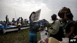 Des personnes embarquent dans des pirogues sur le lac Albert pour fuir les violences en Ituri vers l'Ouganda à Tchomia, le 5 mars 2018.