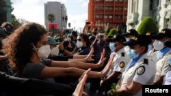 Manifestantes realizan gestos de pacifismo frente a los agentes policiales durante las protestas en Guatemala, el 28 de noviembre de 2020.