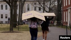 FILE - Students carry boxes to their dorms at Harvard University, after the school asked its students not to return to campus after Spring Break, March 10, 2020, in Cambridge, Massachusetts, U.S.