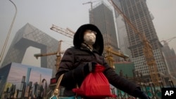 A woman wears a mask as she walks past a construction site as smog continues to choke Beijing, China, Jan. 6, 2017.