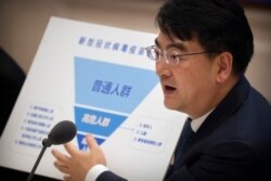 Zheng Zhongwei, from China's National Health Commission, holds a chart showing priority groups for a coronavirus vaccine as he speaks during a press conference to discuss COVID-19 vaccine-related issues on Sept. 25, 2020, in Beijing.