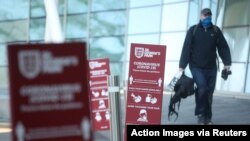 Un hombre camina frente a la señalización de coronavirus fuera de St George's Park. Gran Bretaña, 28 de febrero de 2021.