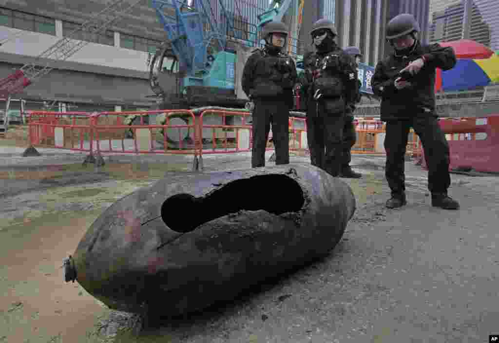 2018年2月1日，在香港湾仔区，处理炸弹的警务人员站在已经拆除爆炸物的的炸弹旁边。这是战争年代留下的一枚未爆炸的炸弹，过去埋在地下。