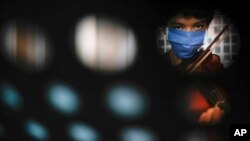 A youth wears a protective face mask amid the new coronavirus pandemic as he plays his violin during free music lessons from Narciso Ernesto Pichardo at the Culture Center in La Pastora neighborhood of Caracas, Venezuela, Aug. 19, 2020. 