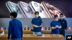 北京一家苹果专卖店2月14日复工后店员们戴着口罩营业。
