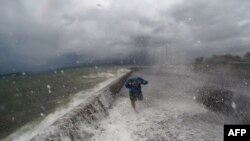 Seorang warga tengah berjalan melewati jalanan yang terkena banjir akibat gelombang besar di kota pantai Legaspi di provinsi Albay, selatan Manila (14/12).