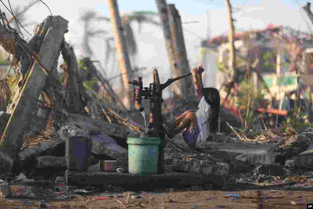 Seorang anak perempuan yang selamat dari topan Haiyan berusaha memompa air minum di kota Tolosa town, provinsi Leyte, Filipina tengah.