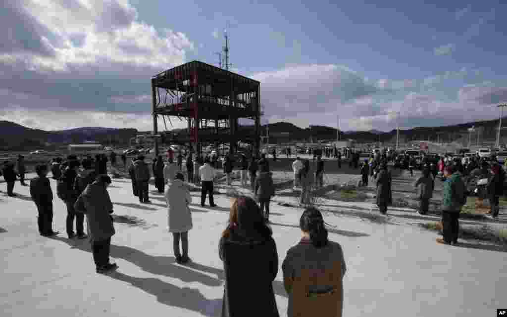 People bow their heads in a moment of silence around what is left of a disaster control center devastated by the March 11, 2011 earthquake and tsunami, Minamisanriku, Miyagi prefecture, Japan, March 11, 2013.
