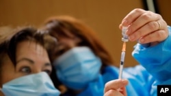 Nurses prepare a Pfizer-BioNTech COVID-19 vaccine to be administered to a health care worker at a coronavirus vaccine center in Poissy, France, Jan.8, 2021. 
