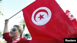 Une femme brandit un drapeau tunisien lors d’un rassemblement contre la violence religieuse et politique en Tunisie, 22 octobre 2012.