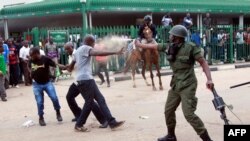 FILE - A police officer fires pepper spray at supporters of the opposition United Party for National Development outside the Woodlands Police Station in Lusaka, March 2, 2016. 
