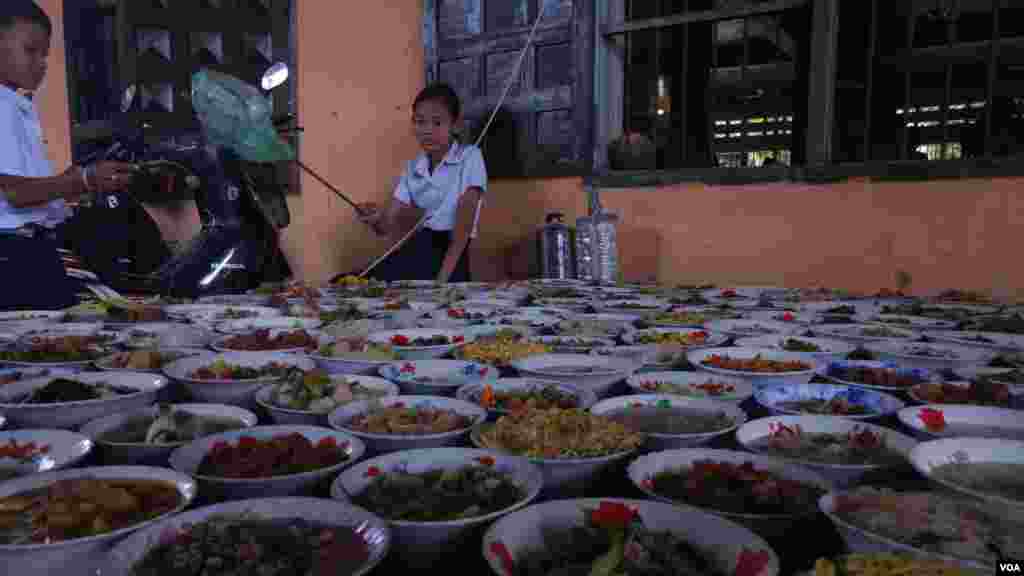 ក្មេងស្រីម្នាក់អង្គុយយាមម្ហូបអាហារដែលពុទ្ទសាសនិកបានយកមកប្រគេនព្រះសង្ឃ ក្នុងឱកាសបុណ្យភ្ជុំបិណ្ឌ នៅវត្តនគរបាជ័យ ខេត្តកំពង់ចាម កាលពីថ្ងៃទី០១ ខែតុលា ឆ្នាំ២០១៦។ (ប៊ុន ប៉េងហ៊ុយ/VOA)