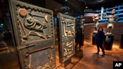 Un visiteur passe devant une porte du palais du roi Gele du royaume du Dahomey, datée du 19e siècle, le Bénin d'aujourd'hui, au musée du Quai Branly à Paris, le 23 novembre 2018.