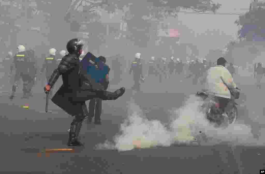 A riot police officer avoids a gas grenade as police fire gas grenades to disperse protesters in Phnom Penh, Jan. 27, 2014.