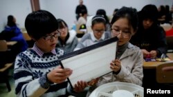 资料照： 在北京一所大学，学生们在练习如何把HEPA过滤网装在风扇上，以自制空气净化器。