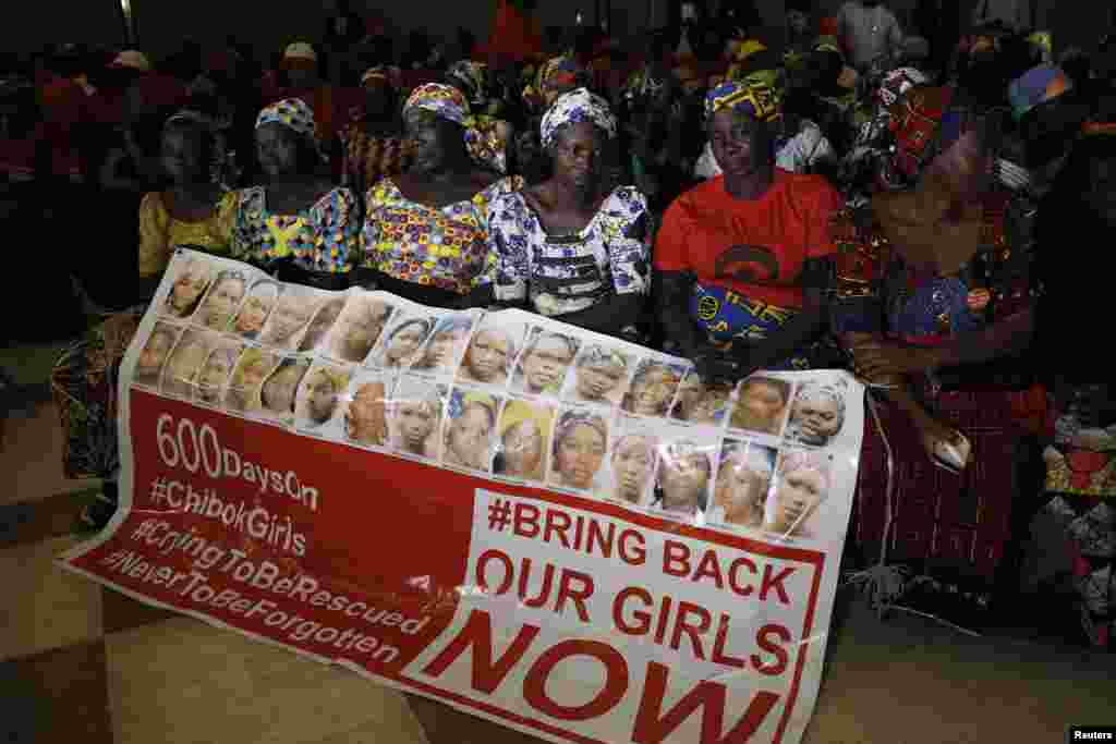 Wasu daga cikin iyayen yaran da 'yan ta'adda suka sace a makarantar Chibok, suna rike da allo dake rubutun bukatar su ta a dawo musu da 'yayansu. a wata ganawa da shugaban kasa Muhammadu Buhari a fadar shugaban kasar ta birnin tarayya Abuja. ranar Alhamis watan Janaaru 14, 2016. 