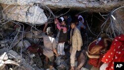 FILE - People search for survivors under the rubble of a house destroyed by Saudi-led airstrikes that killed a TV director, his wife, and three children in Sanaa, Yemen, Feb. 10, 2016.