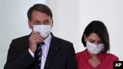 La primera dama de Brasil, Michelle Bolsonaro, junto a su esposo el presidente Jair Bolsonaro, llegan al anuncio de un programa para mujeres rurales, en el palacio de Planalto en Brasilia, el 29 de julio de 2020.