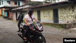Una mujer conduce su motocicleta cerca de una casa que exhibe grafitis del Ejército de Liberación Nacional (ELN) y del frente Oliver Sineterra de disidentes de las Fuerzas Armadas Revolucionarias de Colombia (FARC) en Tumaco, Colombia, 9 de septiembre de 2022. REUTERS/Luisa González