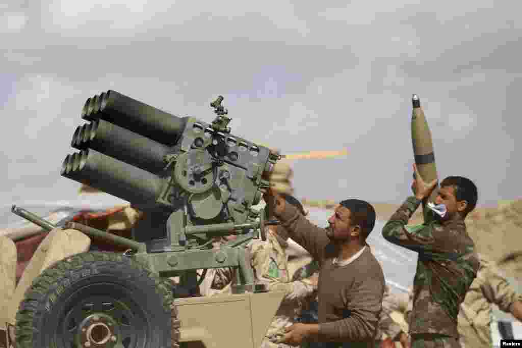 Iraqi security forces and Shi'ite fighters reload a weapon during clashes with Islamic State militants in Saladin province, March 2, 2015.