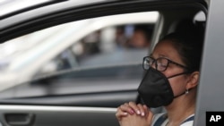 Una mujer que usa una máscara para frenar la propagación del nuevo coronavirus, asiste a una misa en autocine en Chia, Colombia, el domingo 30 de agosto de 2020. 