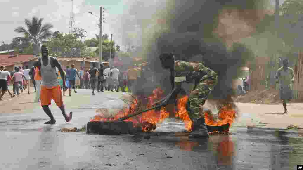 Un soldat de l'armée burundaise tente d'éteindre le feu d'un pneu brulé par les manifestants dans la capitale Bujumbura, Burundi, lundi 27 avril 2015.