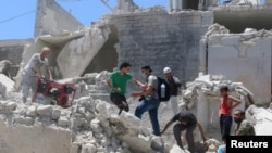 Des habitants marchent dans les ruines d'Alep, Syrie, le 11 juillet 2016. 