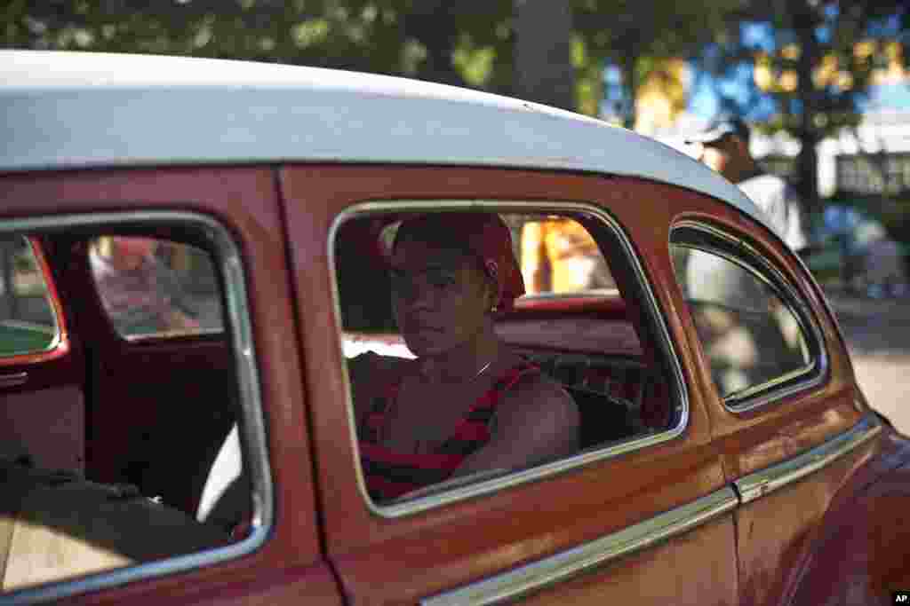 A woman waits in a classic American car that's used as a shared taxi by commuters in Havana, Cuba, Dec. 18, 2014.