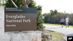 Visitors walk past a sign for Everglades National Park as they enter from overflow parking, Wednesday, Jan. 2, 2019, in Everglades National Park, Fla. Biden released a plan described in a report called “America the Beautiful.”
